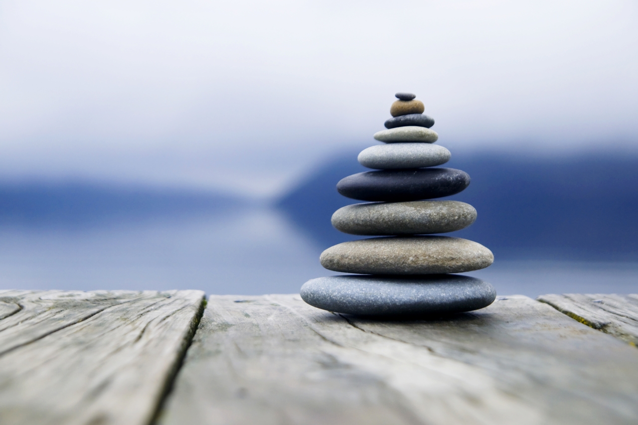 Zen balancieren von kieselsteinen neben einem nebligen See